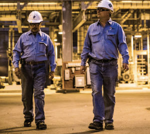 two men walking wearing industrial and manufacturing uniforms